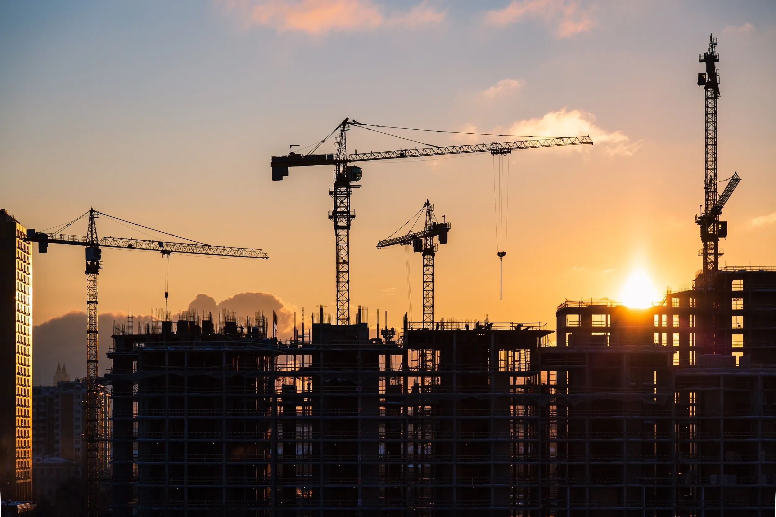Construction site with cranes at sunset — development capital projects